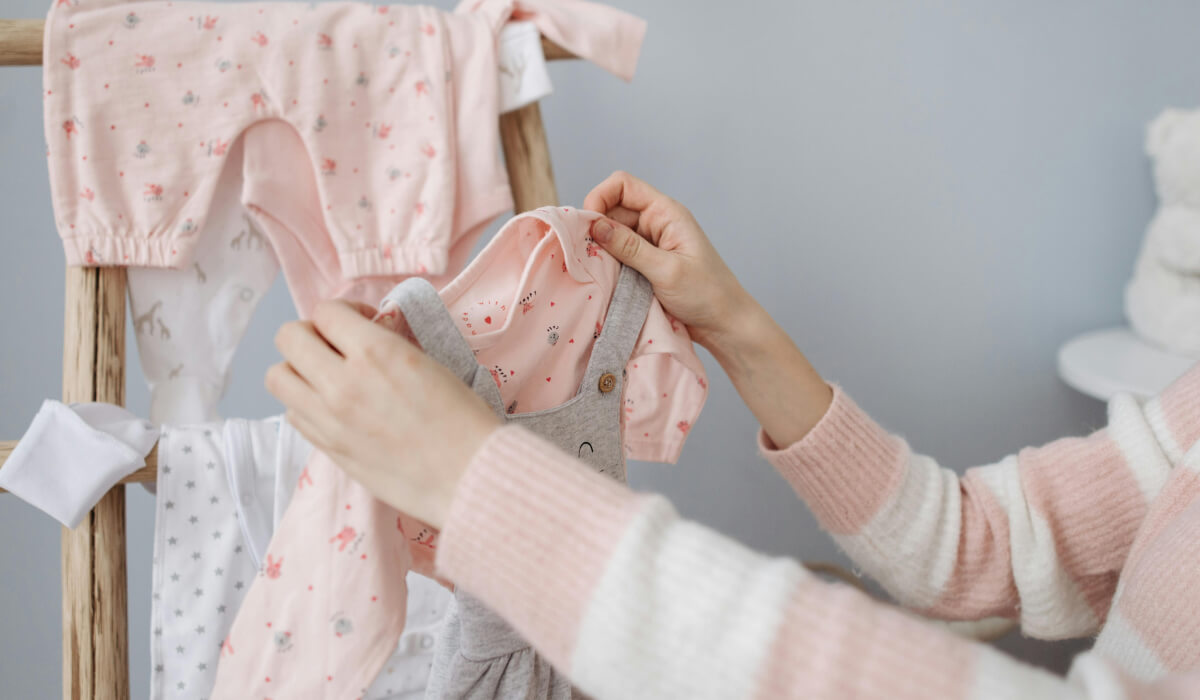 Baby Erstausstattung - Eine Mutter sortiert Babykleidung
